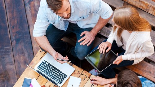 drei Personen arbeiten mit Laptop und Tablet 