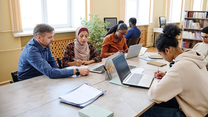 mehrere Personen sitzen an einem Tisch und arbeiten 