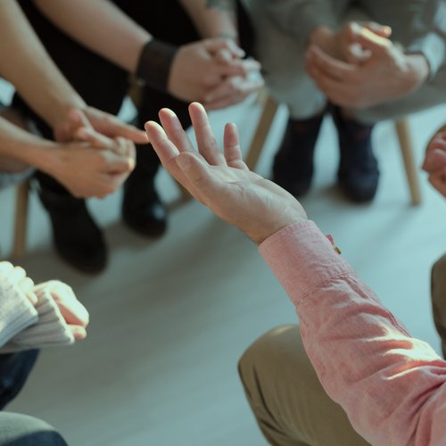 Hände von im Kreis sitzenden Personen