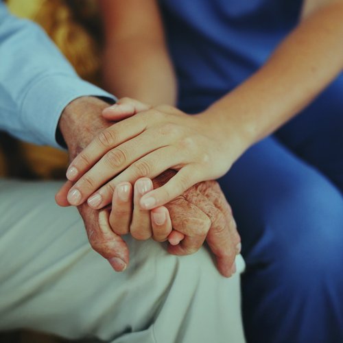 Hand einer jungen Person liegt auf der Hand einer alten Person