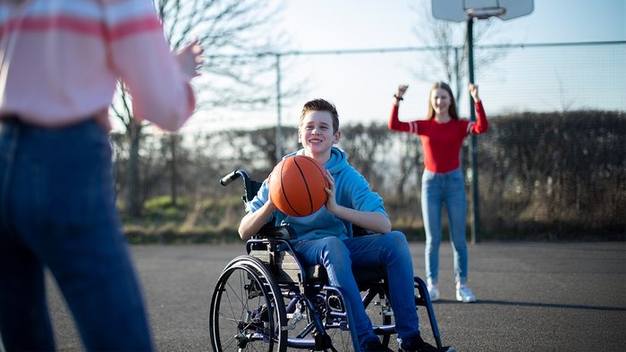 Kind im Rollstuhl hält einen Basketball