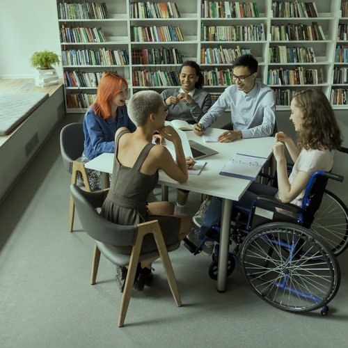 5 junge Personen sitzen um einen Tisch