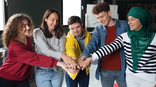 fünf junge Erwachsene strecken ihre Hände in die Mitte