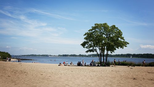 Menschen liegen an einem See im Sand